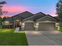 Charming single-story home with a three car garage and well-manicured lawn and stone facade at 6957 Boulder Run Loop, Wesley Chapel, FL 33545