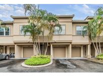 Townhome exterior featuring a beige facade, driveways, attached garages, and a small landscaping island with palm trees at 820 Normandy Trace Rd, Tampa, FL 33602