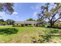 Charming ranch-style home with a well-manicured lawn and lush greenery on a sunny day at 9918 Davis Rd, Tampa, FL 33637