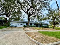 Charming single-story home featuring a two-car garage and mature trees in a well-manicured front yard at 1005 Apache Trl, Clearwater, FL 33755