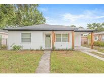 Charming single-story home with fresh white brick, natural wood posts, green door, and a well-manicured lawn at 1713 W Saint John St, Tampa, FL 33607