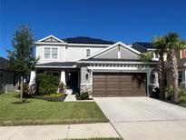 Two-story home boasts a well-manicured lawn, palm trees, a two-car garage and solar panels at 33560 Castaway Loop, Wesley Chapel, FL 33543