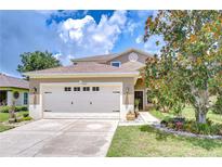 Inviting front exterior with a two-car garage, manicured lawn, and beautiful landscaping at 4227 Bethpage Ct, Wesley Chapel, FL 33543