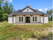 Charming exterior featuring a covered front porch with wooden beams and a modern black front door at 4261 Burns Rd, Brooksville, FL 34602