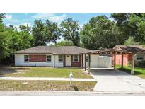 Charming single-story home featuring brick accents, a cozy carport, and a well-maintained front lawn at 4425 Porpoise Dr, Tampa, FL 33617