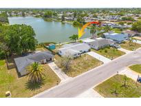 Aerial view of waterfront home with a large yard, mature trees and a beautiful lake view at 8014 Lotus Dr, Port Richey, FL 34668