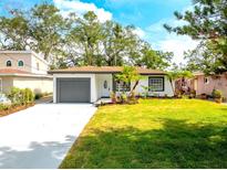 Charming single-story home with lush green lawn, a gray garage door, and well-manicured landscaping at 8335 42Nd N Ave, St Petersburg, FL 33709