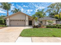 Charming single-story home featuring a two-car garage, manicured lawn, and tropical landscaping at 1 Mandarin Ter, Safety Harbor, FL 34695
