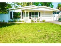 Charming single-story home with well-manicured lawn and inviting front porch seating area at 135 Emerald Ln, Largo, FL 33771