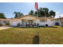 Charming single-story home with a well-maintained lawn, American flag, and inviting front porch at 2135 Pocahontas Dr, Largo, FL 33774