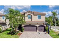 Two-story home featuring a three-car garage, paver driveway, neutral stucco, and manicured landscaping at 2388 Oakwood Preserve Dr, Wesley Chapel, FL 33543