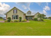 Inviting exterior of home featuring a lush lawn, mature landscaping, and charming architectural details at 3212 E Merrin Rd, Plant City, FL 33567