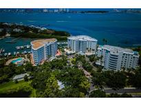 Stunning aerial view of waterfront condos with boat docks and lush landscaping with a city skyline in the background at 1 Seaside Ln # 302, Belleair, FL 33756