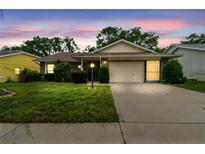 Charming single-story home with manicured lawn and attached two-car garage at twilight at 13127 Topflite Ct, Hudson, FL 34669