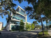 Modern building exterior, surrounded by lush greenery under a clear blue sky, promising a luxurious urban living experience at 132 Mirror Lake N Dr # 501, St Petersburg, FL 33701