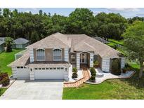 Charming two-story home featuring a manicured lawn, beautiful landscaping, and a two-car garage at 1460 Kensington Woods Dr, Lutz, FL 33549