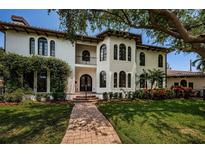 Elegant stucco home features arched windows, a Juliet balcony, and lush landscaping at 147 Bay Point Ne Dr, St Petersburg, FL 33704