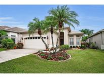 Charming home featuring a two-car garage, palm trees, and well manicured landscaping at 1528 Riverdale Dr, Oldsmar, FL 34677