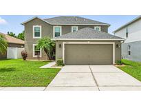 Beautiful two-story home with a well-manicured lawn, large garage, and attractive landscaping at 30317 Rattana Ct, Wesley Chapel, FL 33545