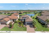 An aerial view of a single-Gathering home with a lush green lawn, terracotta roof, and serene lake backdrop at 3167 Forsythia Dr, Odessa, FL 33556