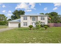 Two-story stucco home featuring a light metal roof, attached garage and manicured lawn at 3411 Landover Blvd, Spring Hill, FL 34609
