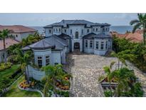 An eye-level view of a luxurious waterfront home featuring manicured landscaping, a spacious driveway, and stunning architectural details at 6526 Surfside Blvd, Apollo Beach, FL 33572