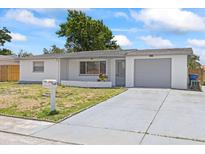 Charming single-story home with a well-maintained lawn and a one-car garage on a sunny day at 7330 Abalone Dr, Port Richey, FL 34668