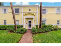 Charming condominium entrance featuring yellow walls and manicured landscaping along the brick path at 101 Pompano Se Dr # C, St Petersburg, FL 33705