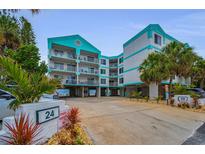 Beautiful, multi-story beach condo with private parking, lush landscaping, and teal and white color scheme at 24 Gulf Blvd # 1C, Indian Rocks Beach, FL 33785
