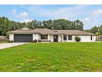 Charming single-story home featuring a lush green lawn, dark garage door, and well-maintained landscaping at 25555 Oaks Blvd, Land O Lakes, FL 34639