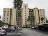 Spacious condo complex featuring palm trees, covered parking, and serene landscaping at 2616 Cove Cay Dr # 104, Clearwater, FL 33760