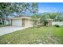 Charming single-story home with a two-car garage, stone accents, and well-maintained lawn at 3021 Jarvis St, Holiday, FL 34690