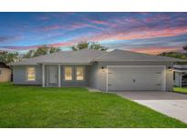 Charming single-story home with a well-manicured lawn, attached garage, and a colorful sunset backdrop at 5319 Lantana St, Zephyrhills, FL 33542
