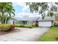 Charming single-story home with a well-manicured front yard and a circular driveway leading to the two-car garage at 5871 Oakhurst Dr, Seminole, FL 33772