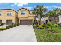 Charming tan two-story townhome with well-manicured landscaping and a large driveway at 6031 Grand Sonata Ave, Lutz, FL 33558