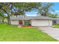 Charming single-story home featuring a well-manicured lawn, mature trees and a two-car garage at 6058 Waycross Dr, Spring Hill, FL 34606
