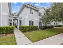 Charming exterior townhome with manicured green lawn, pathway and lovely neutral paint at 7410 E Bank Dr, Tampa, FL 33617