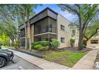 Inviting condo exterior featuring a screened balcony surrounded by lush landscaping and mature trees at 11805 Raintree Lake Ln # A, Tampa, FL 33617