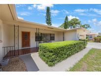Charming front exterior with a quaint porch, lush hedges, and a decorative front door at 1305 Marion S Dr, St Petersburg, FL 33707