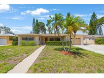 Charming single-story home with a well-manicured lawn, palm trees, and a cozy front entrance at 1305 Marion S Dr, St Petersburg, FL 33707