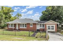 Charming brick home with a well-maintained lawn, and a chain-link fence around the yard at 1511 Emma E St, Tampa, FL 33610