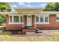 Charming brick home featuring a covered entry with decorative metal support columns and large windows at 1511 Emma E St, Tampa, FL 33610