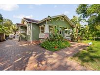 Charming green home with brick walkway, lush landscaping, and inviting curb appeal at 216 W South Ave, Tampa, FL 33603