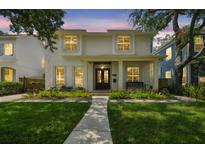 Charming two-story home featuring a manicured lawn, lush landscaping, and a welcoming front porch with a bench at 2522 W Watrous Ave, Tampa, FL 33629