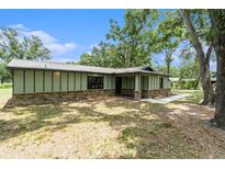 Charming single-story home featuring stone accents and a metal roof in a serene, wooded setting at 5106 Five Acre Rd, Plant City, FL 33565