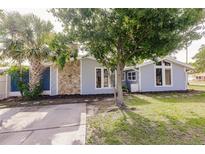 Charming single-story home featuring stone accents, mature trees and a lush lawn at 647 74Th N Ave, St Petersburg, FL 33702
