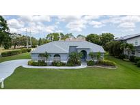 Beautiful single-story home with blue exterior, arched windows, manicured lawn and palm trees at 8679 Burning Tree Cir, Seminole, FL 33777