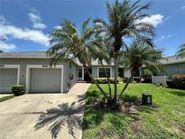 Charming home exterior featuring a garage, tropical landscaping, and a brick walkway at 907 San Carlos Ne Ave, St Petersburg, FL 33702