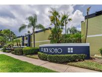 Exterior view of the building's facade featuring lush landscaping and a modern design against a backdrop of palm trees and blue skies at 1301 S Howard Ave # A22, Tampa, FL 33606