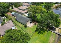 Spacious fenced backyard featuring green grass, mature trees, and a home with a lovely deck and lake access at 14808 Lake Magdalene Cir, Tampa, FL 33613